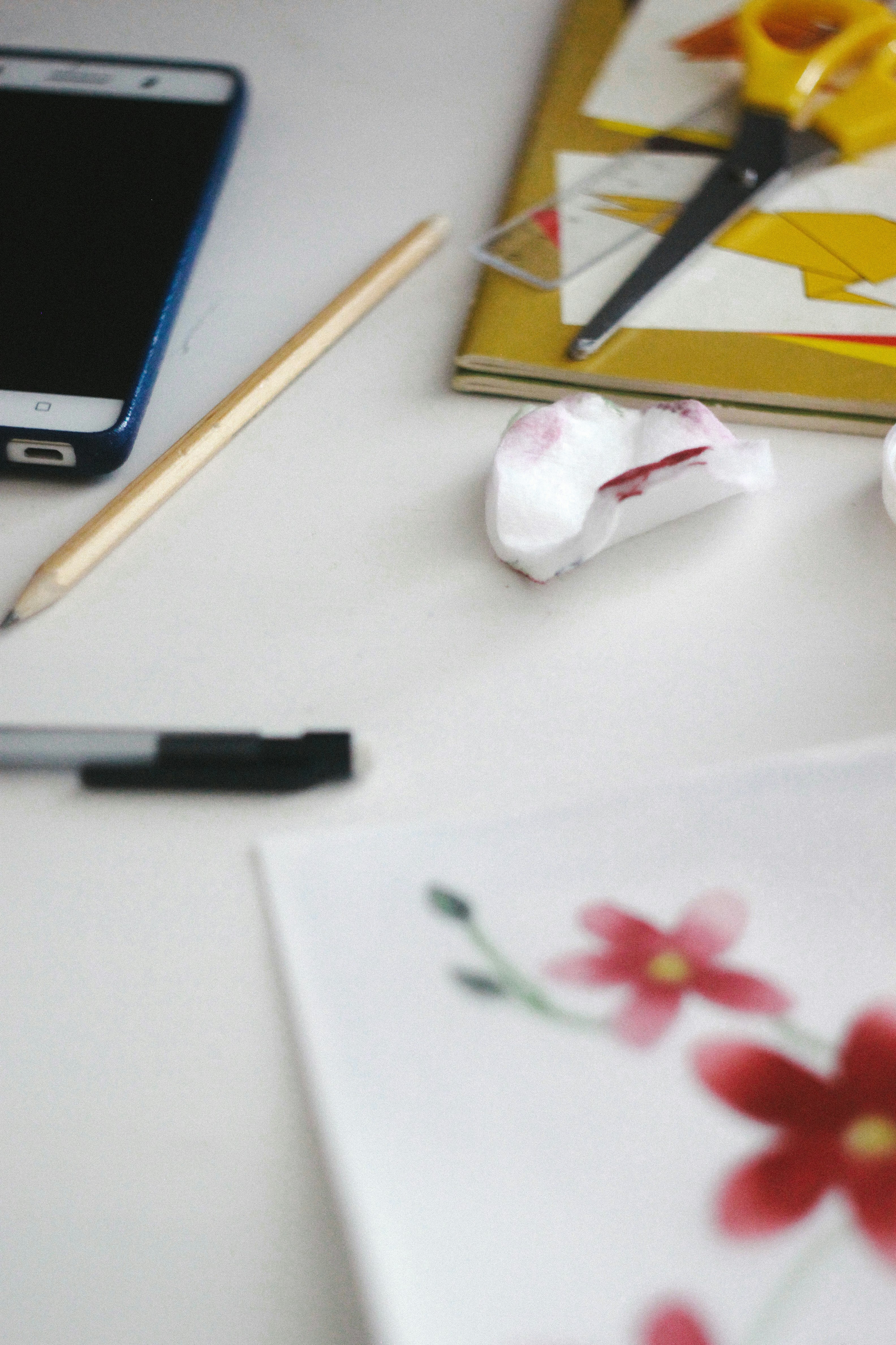 black click pen beside white and red flower on white table